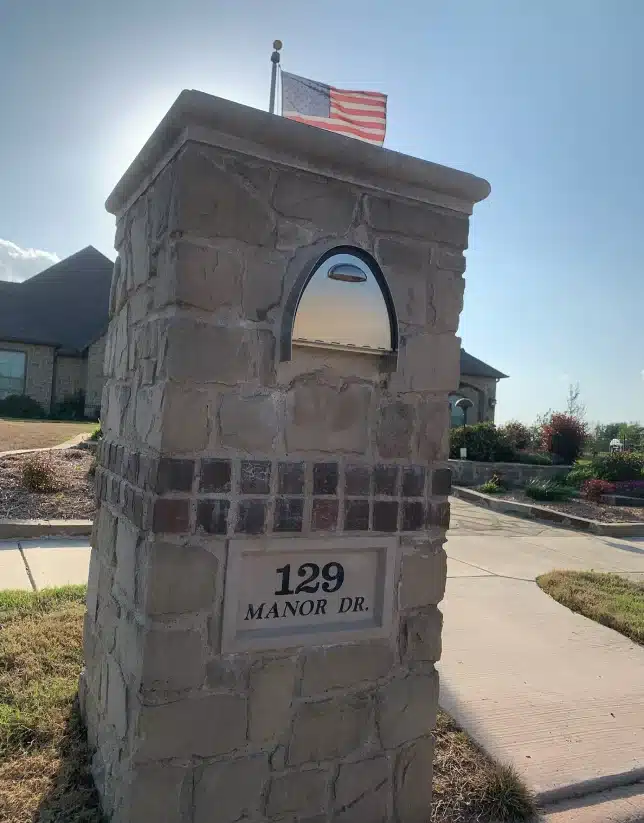 Stone mailbox with cast stone and address plaque in front of a house